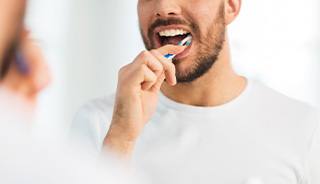 Man smiling while brushing his teeth