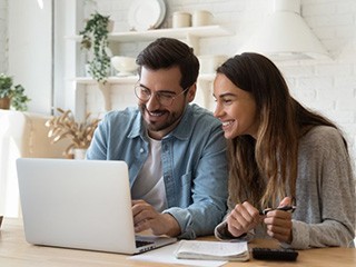 Man and woman looking at a laptop and smiling