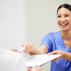 dental assistant smiling while handing patient form