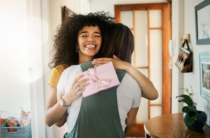 Young woman smiles and embraces her friend after receiving a birthday present